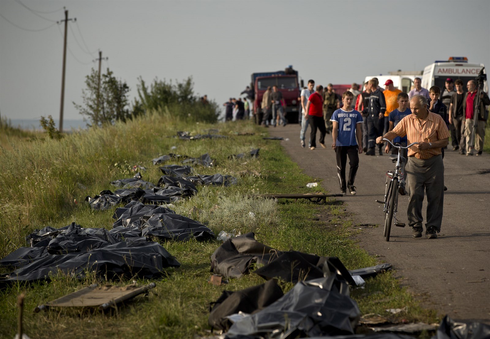 Tla obtí z MH17 leí v plastikových pytlích podél cesty.