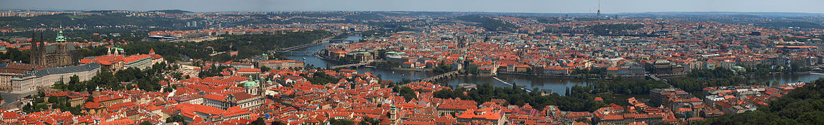 Panorama Prahy z Petřínské rozhledny. Vlevo jsou vidět Hradčany s Pražským hradem, jemuž dominuje svatovítská katedrála, pod nimi se rozkládá Malá Strana. Ve středu snímku pražský záhyb Vltavy obklopuje Staré Město. U horizontu leží Severní Město, Letná a Holešovice, Karlín, Vinohrady, Nové Město, Žižkov, Pankrác, Podolí i další čtvrti. V popředí snímku jsou zahrady vrchu Petřína, vpravo Růžový sad s věžemi starokatolického katedrálního kostela svatého Vavřince, Hladovou zdí, hvězdárnou a horní stanicí lanovky.